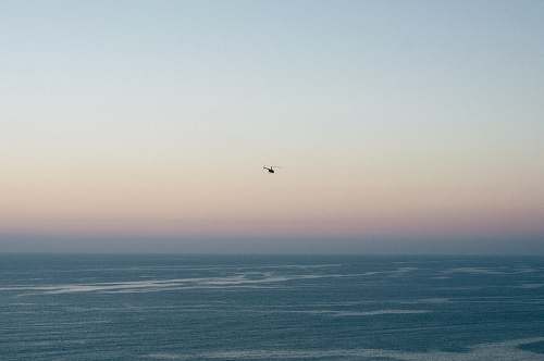grey photo of helicopter hovering above body of water torrey pines state reserve